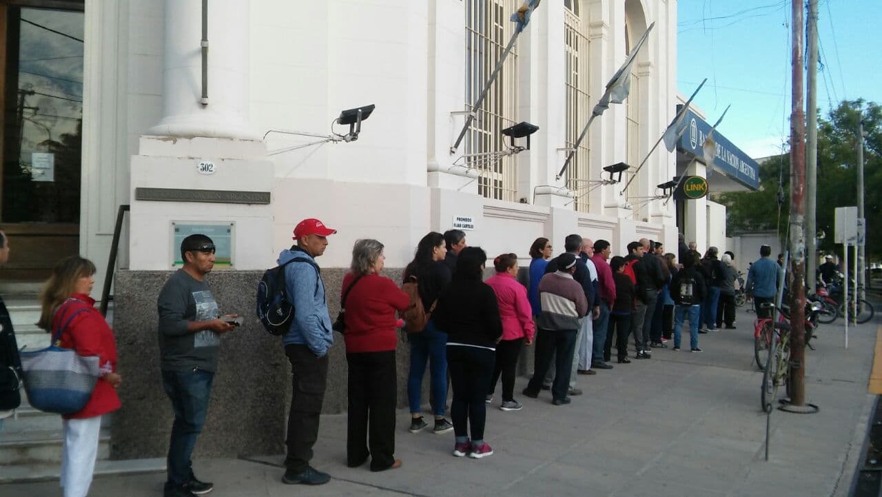 Vecinos y vecinas hacen largas colas para sacar un número en el Banco Nación